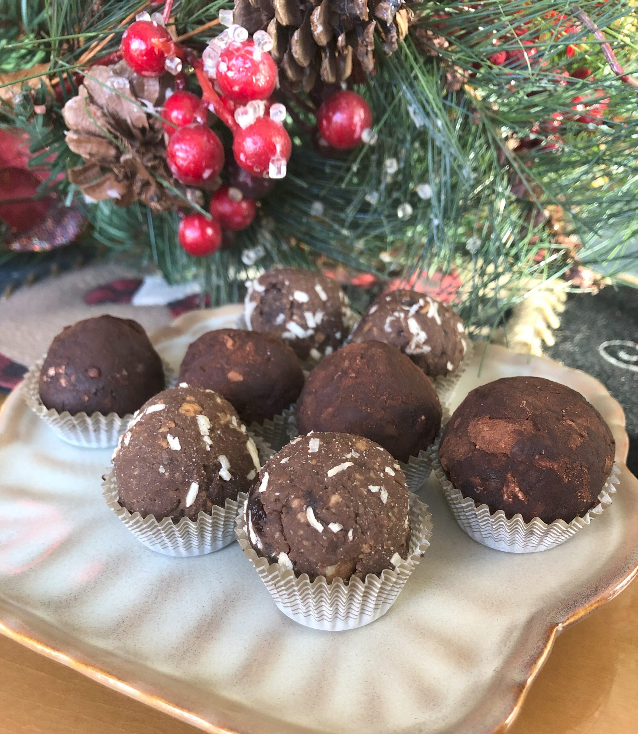 Rum Balls Cookies arranged on a plate surrounded by Christmas decor.