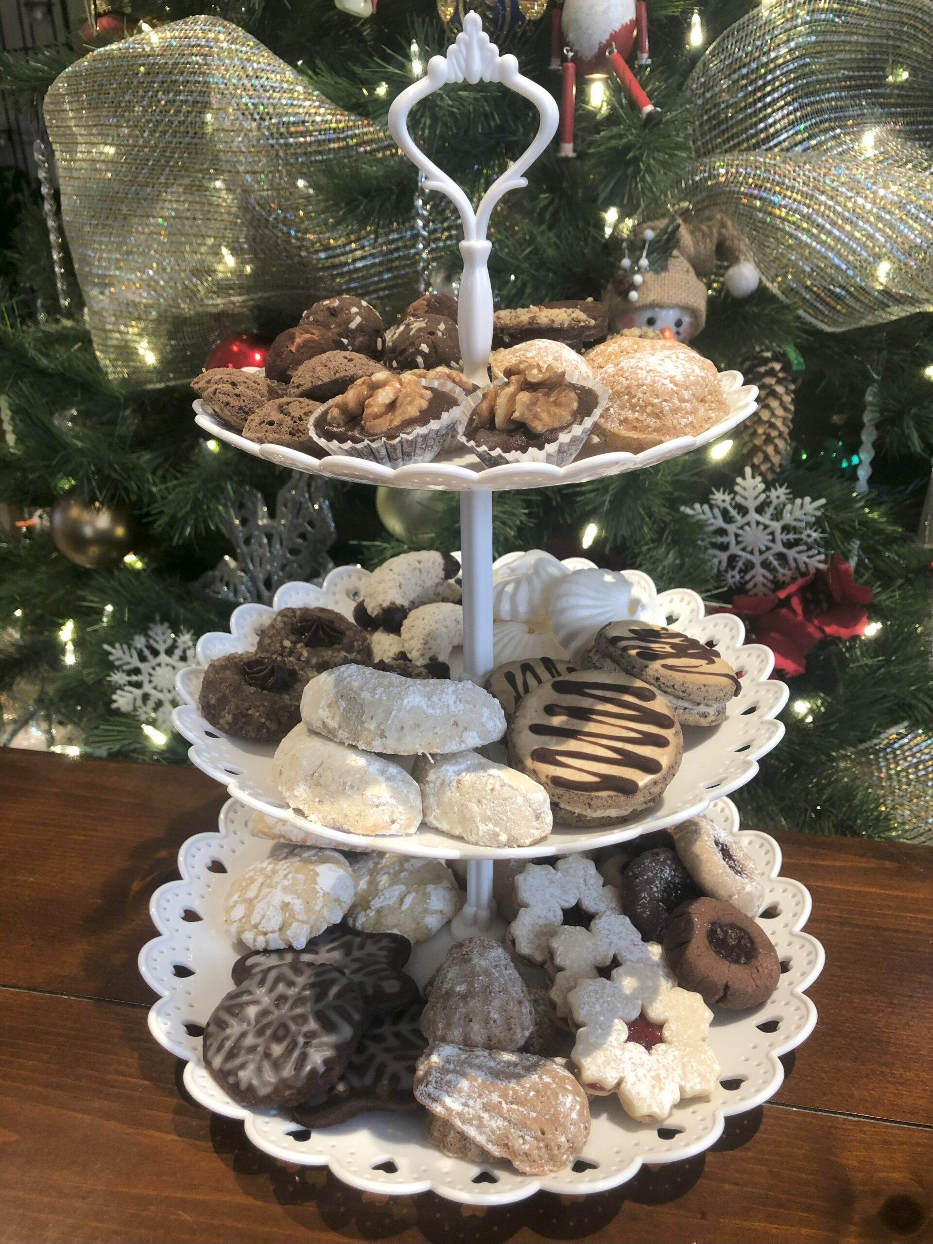 Christmas cookies on 3-tiered plate on holiday decorated table.